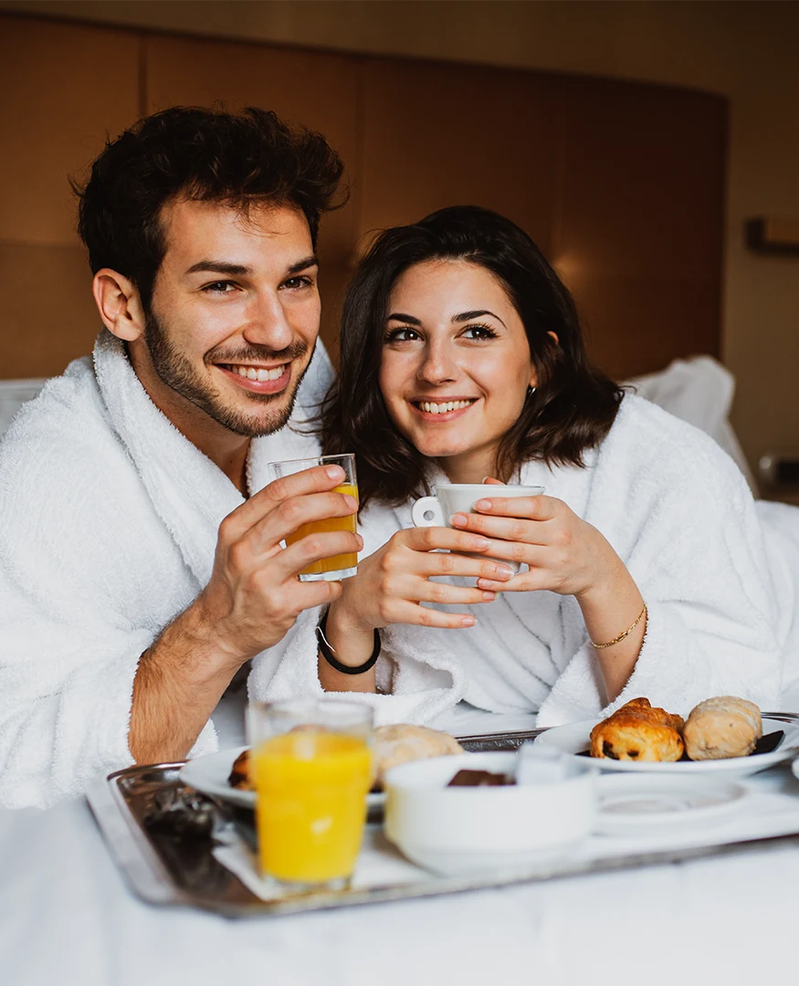 Imagen de dos personas disfrutando de un desayuno en su habitación de hotel